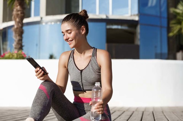 Outdoor shot of happy fitness woman looking at mob sjyccsg display